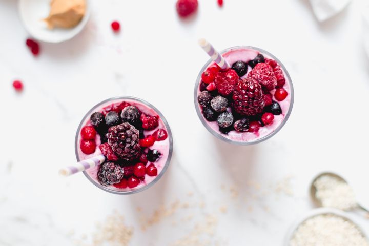 Protein packed banana berry smoothie with yogurt served in two glasses with berries on top.