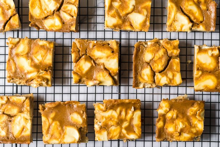 Pumpkin cream cheese bars with a pie crust base sliced into squares on a wire baking rack.