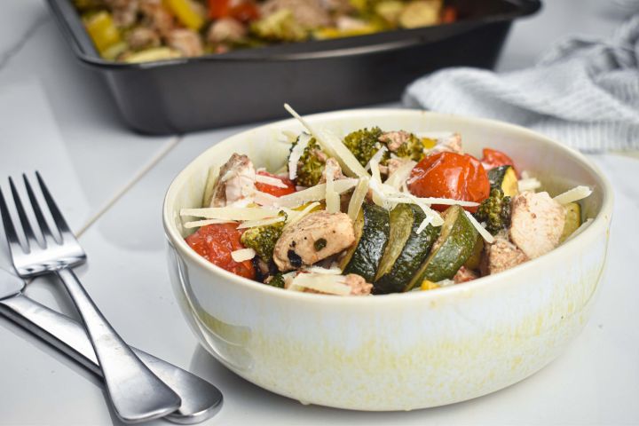 Italian chicken and vegetables in a bowl with Parmesan cheese.