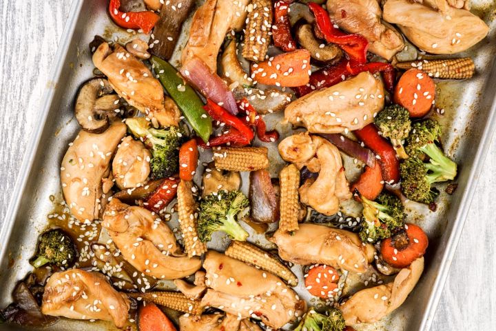Sheet pan Asian chicken stir fry with chicken breast, peppers, broccoli, and other veggies on a sheet pan.
