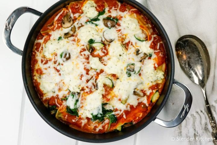 Skillet vegetable lasagna in a pan with zucchini, spinach, mushrooms, and melted cheese.