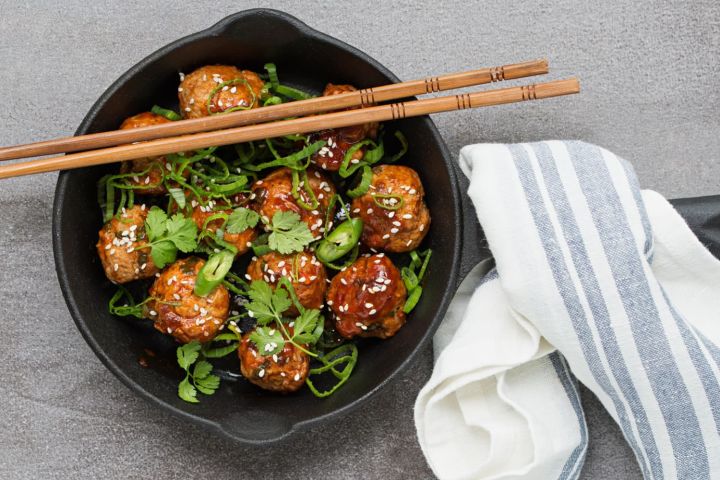 Slow Cooker Asian Meatballs in a skillet with cilantro and green onions on top.