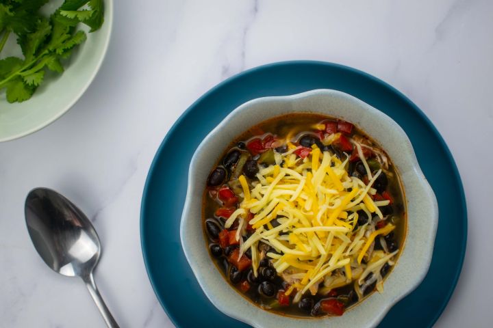 Slow Cooker Chicken Enchilada Soup with shredded cheese and cilantro.