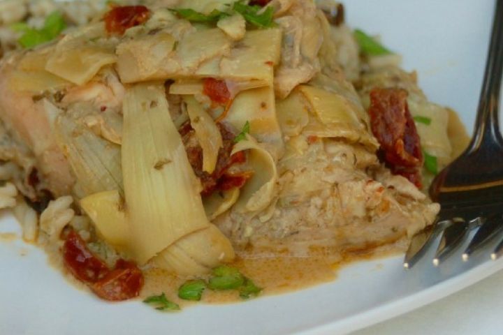 Slow Cooker Green Goddess Chicken with artichokes on a plate with sundried tomatoes.