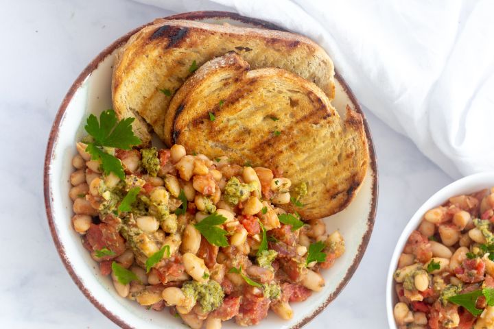 Stewed basil white beans with tomatoes, onions, garlic, and pesto sauce with garlic bread.