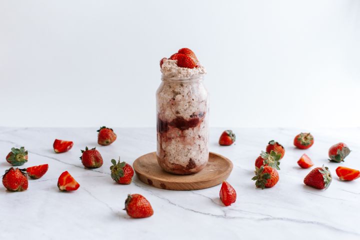 Strawberry overnight oatmeal with rolled oats and chia seeds in a mason jar with fresh strawberries and cream.