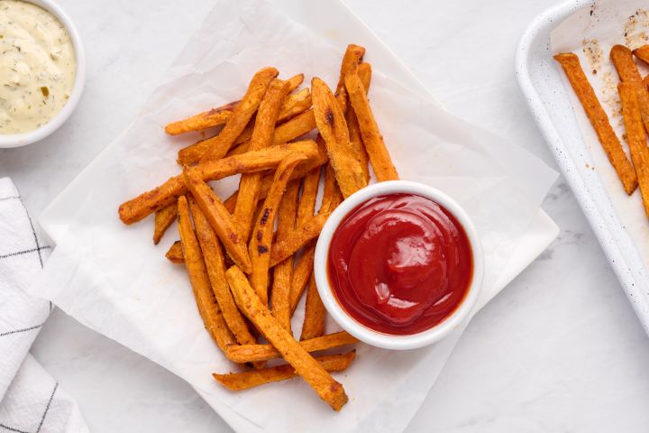Baked sweet potato fries with a crispy exterior on a plate with ketchup.