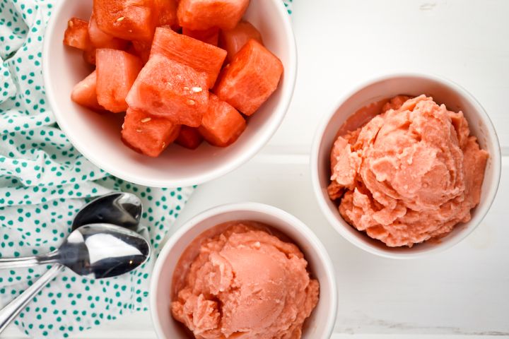 Watermelon ice cream in two white bowls with a spoon.
