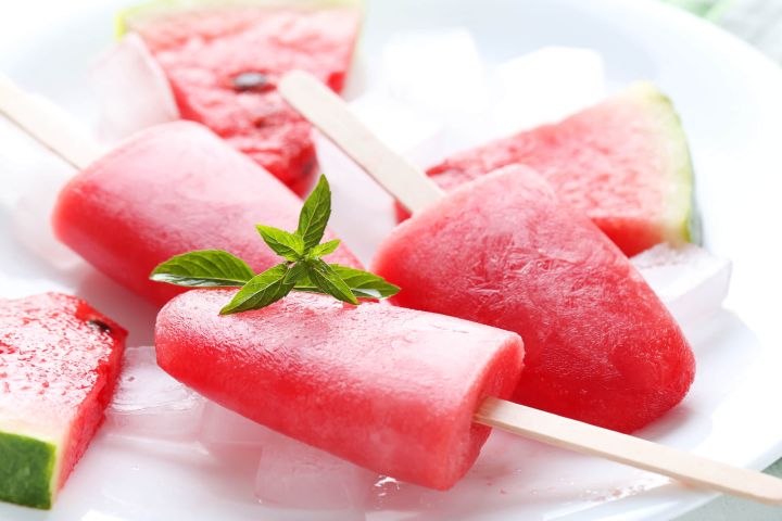 Two watermelon popsicles with a block of ice.