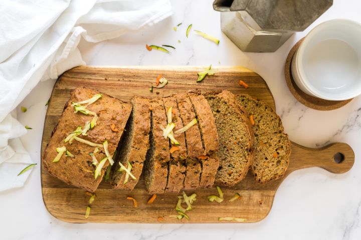 Zucchini carrot bread made with shredded zucchini, carrots, and whole wheat flour sliced on a wooden cutting board.