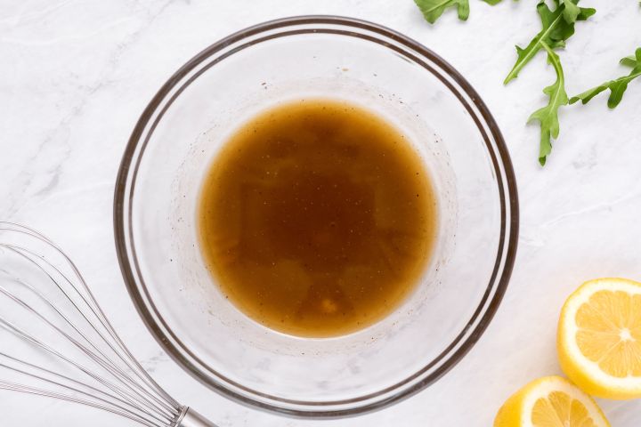 Balsamic vinaigrette with lemon juice, balsamic vinegar, honey, and olive oil in a glass bowl.