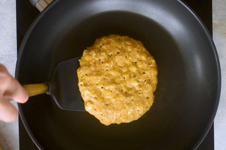 Banana oat pancakes cooking in a skillet. 