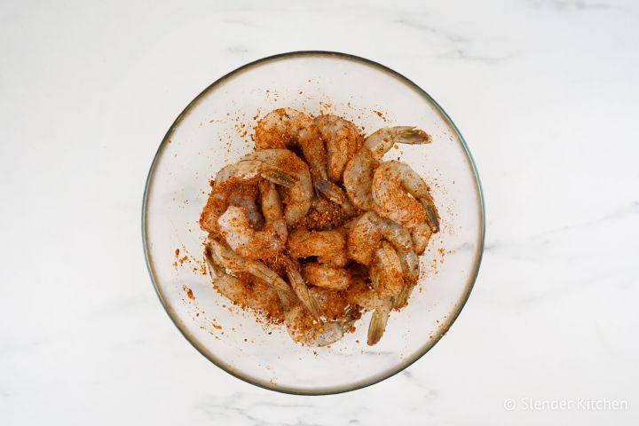Shrimp tossed in cajun seasoning in a glass bowl.
