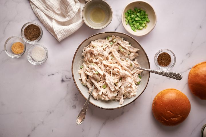 Chicken salad being mixed with a spoon in a bowl.