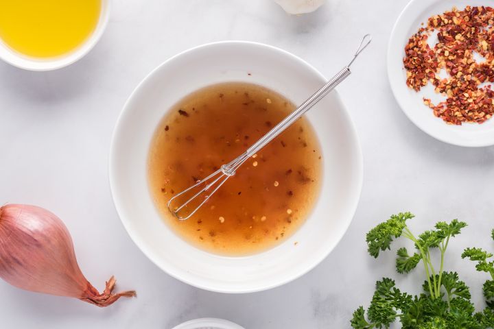 Red wine vinegar, olive oil, and chicken broth in a small bowl.