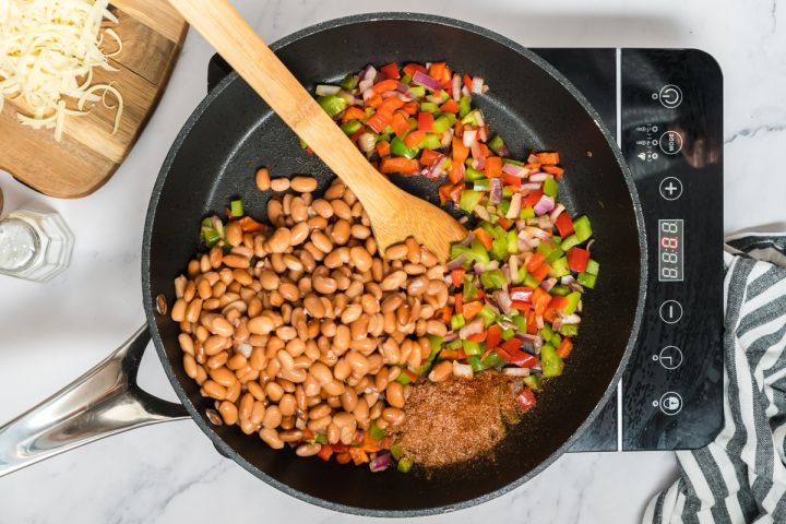 Pinto beans, peppers, onions, and fajita seasoning cooking in a skillet.