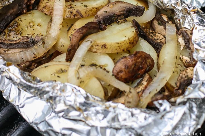 Grilled potatoes and onions in an open foil packet on the grill. 