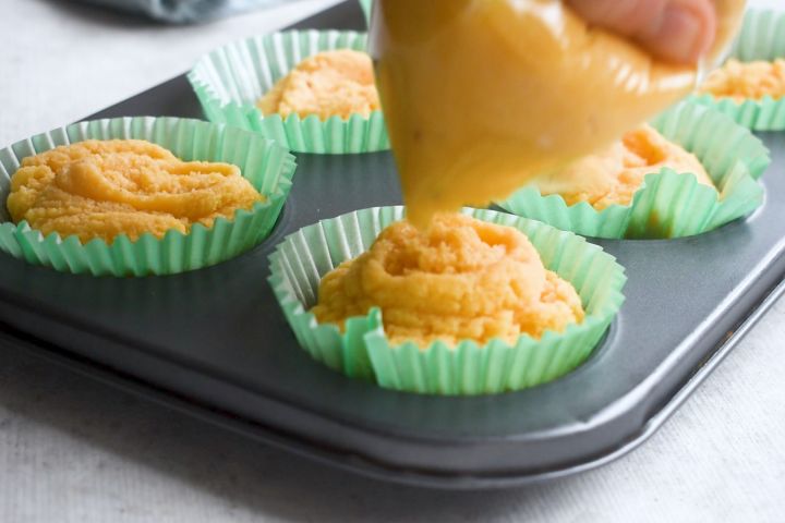 Coconut batter being added to a muffin tin.
