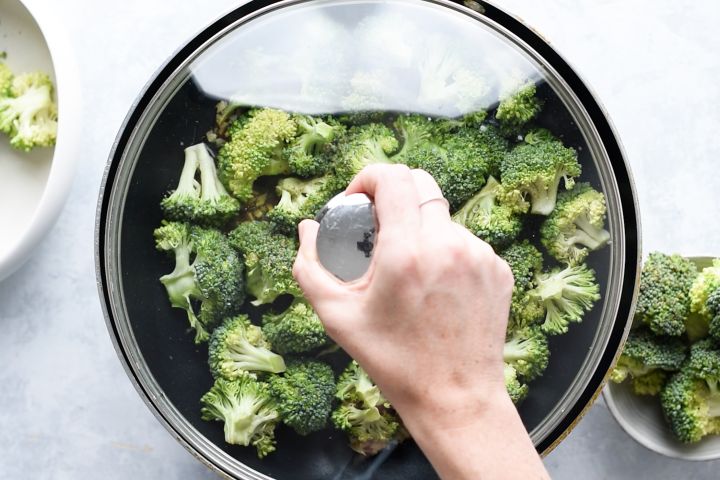 Broccoli in a skillet with water that is covered.