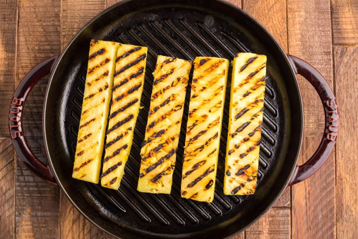 Pineapple grilling on a cast iron skillet.