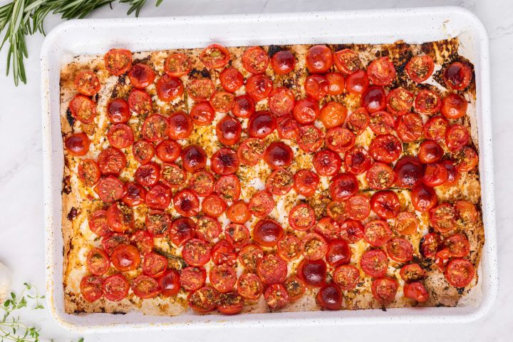 Roasted grape tomatoes with garlic, olive oil, and Italian seasoning on a baking sheet.