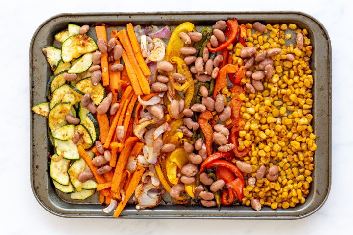 Cook roasted vegetables for fajitas on a baking sheet with seasoning.