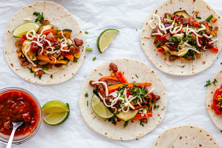 Roasted vegetable fajitas in flour tortillas with salsa, cheese, and limes.
