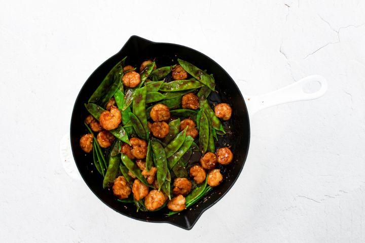 Sesame shrimp and snow peas cooked in a skillet.