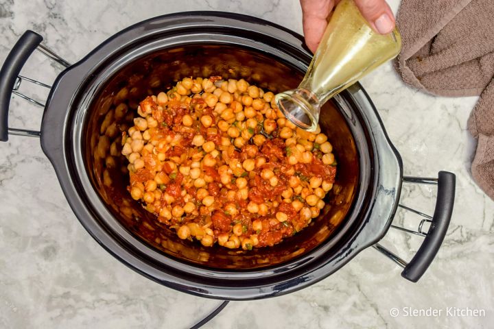 Lemon juice being poured over cooked chickpeas in chana masala sauce.