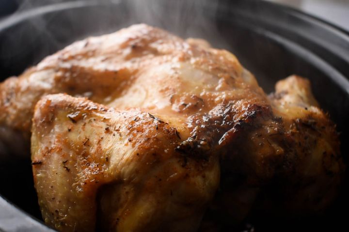Slow cooker rotisserie chicken covered with lemon juice and spices.
