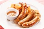 Cooked sausages with dipping sauce on a white plate