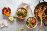 Chipotle Sofritas tofu in a skillet and served in bowls with lettuce, avocado, tomato, and cilantro.