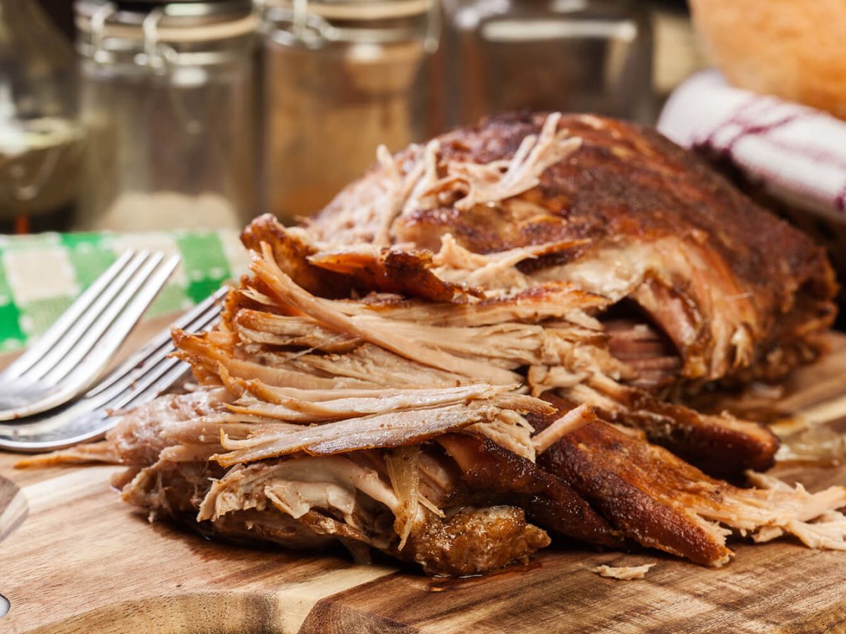 Slow cooked pulled pork shoulder on chopping board