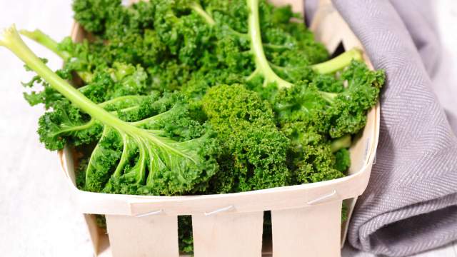 Kale in a wooden basket with a gray napkin.