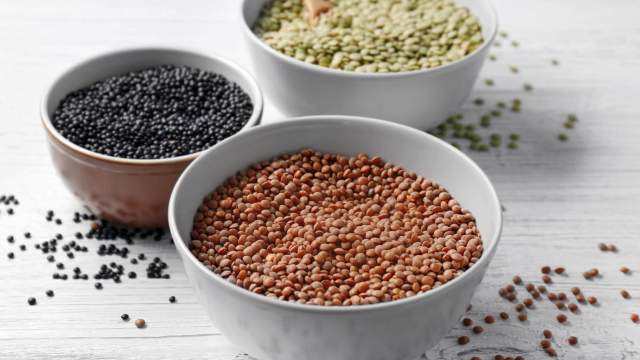 Three types of lentils including brown, black, and green in bowls.