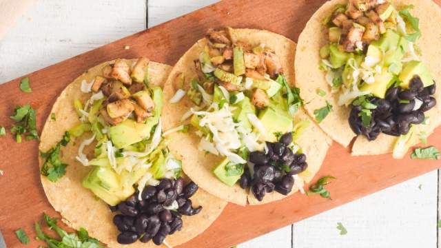 Black bean and zucchini tacos with avocado and cabbage slaw on corn tortillas.