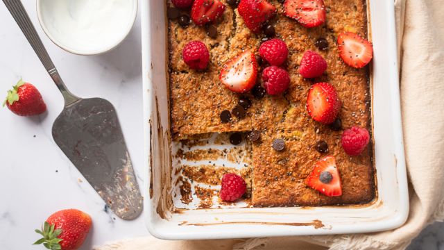 Baked oatmeal made with rolled oats in a baking dish with raspberries, strawberries, and chocolate chips.