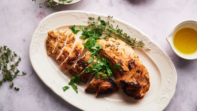 Baked turkey tenderloin sliced on a plate with fresh herbs,
