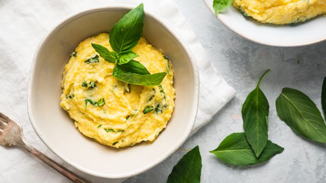 Basil Parmesan polenta in a bowl with fresh basil leaves on top.