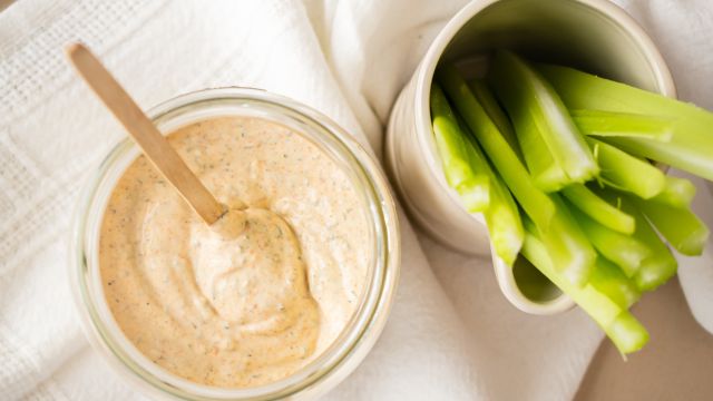 Blackened ranch dressing with yogurt and buttermilk in a glass jar with celery sticks.