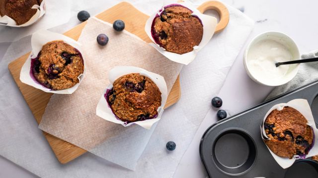 Blueberry oatmeal muffins with fresh blueberries in parchment paper on a cutting board.