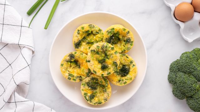 Broccoli Cheddar Egg Muffins with broccoli florets , green onions, and shredded cheese. 