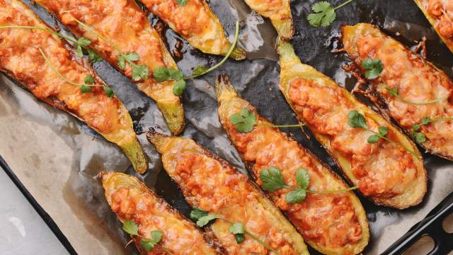 Chicken Parmesan zucchini boats with ground chicken, tomatoes, and melted cheese on a baking sheet.