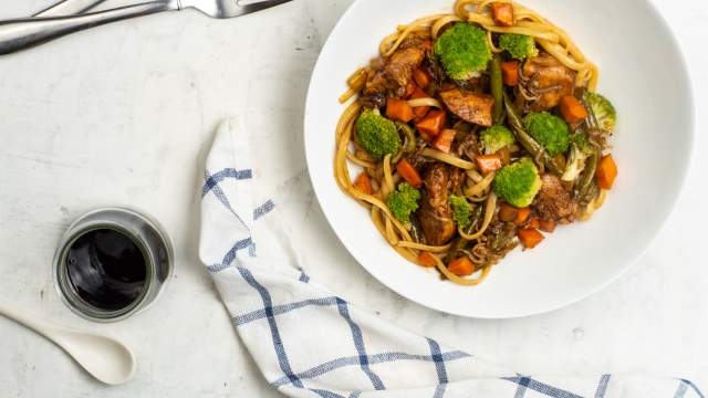 Healthy chicken lo mien with broccoli on a white plate with soy sauce.