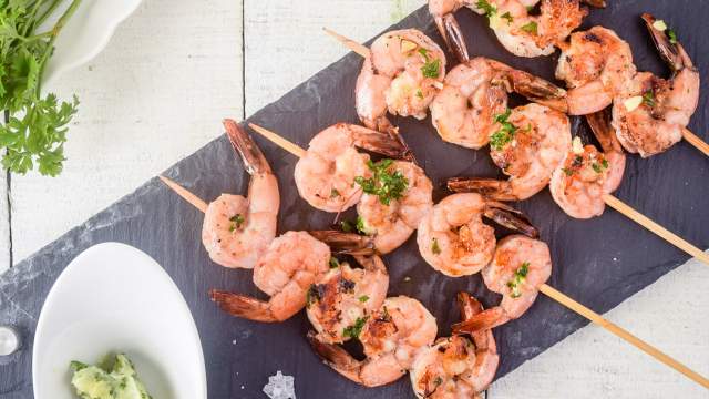 Garlic lemon shrimp kabobs on a piece of slate with garlic and parsley.