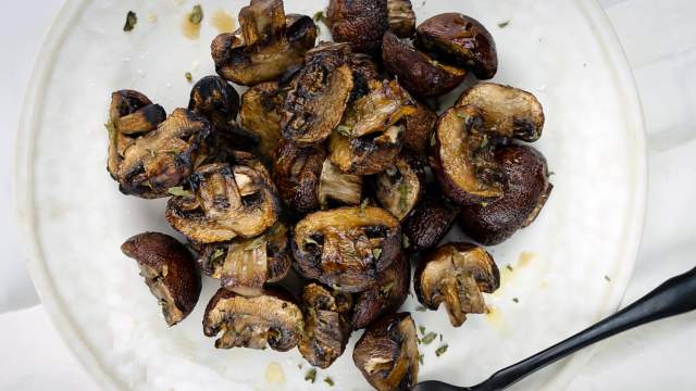 Grilled mushrooms with balsamic vinegar, olive oil, and garlic on a plate.