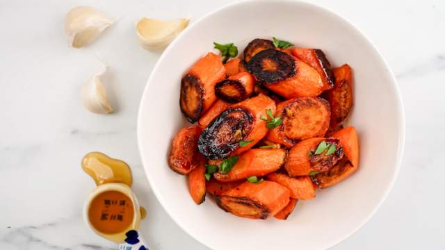 Honey garlic roasted carrots in a bowl with parsley. 