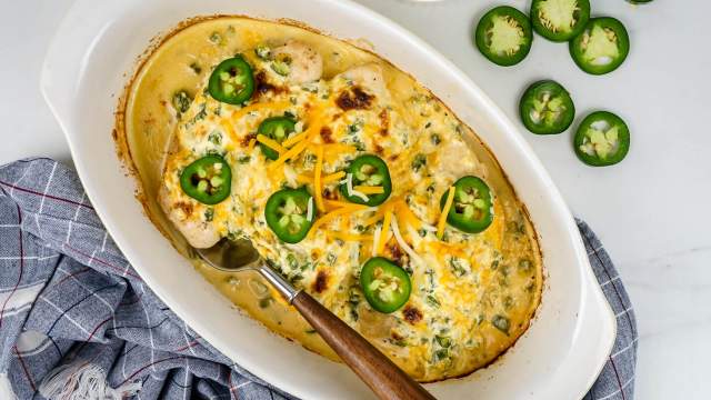 Jalapeno Popper Chicken with cream cheese, cheddar cheese, jalapeno, and chicken breast in a casserole dish.