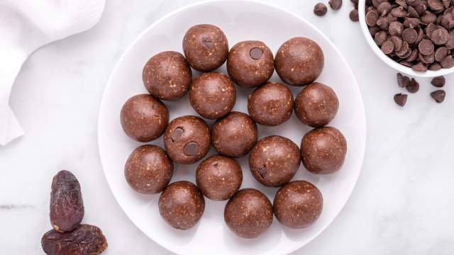 Date Brownie Bites with chocolate chips, Medjool dates, cashews, and almonds on a plate.