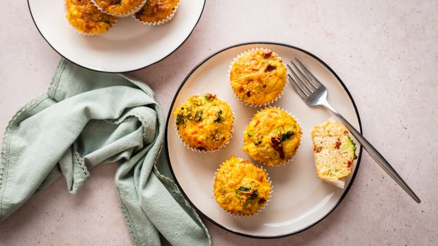 Quinoa egg muffins with cooked quinoa, eggs, broccoli, sundried tomatoes, and shredded cheese served on a plate.